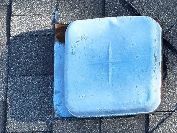 Close-up of a metal box vent on a shingle roof